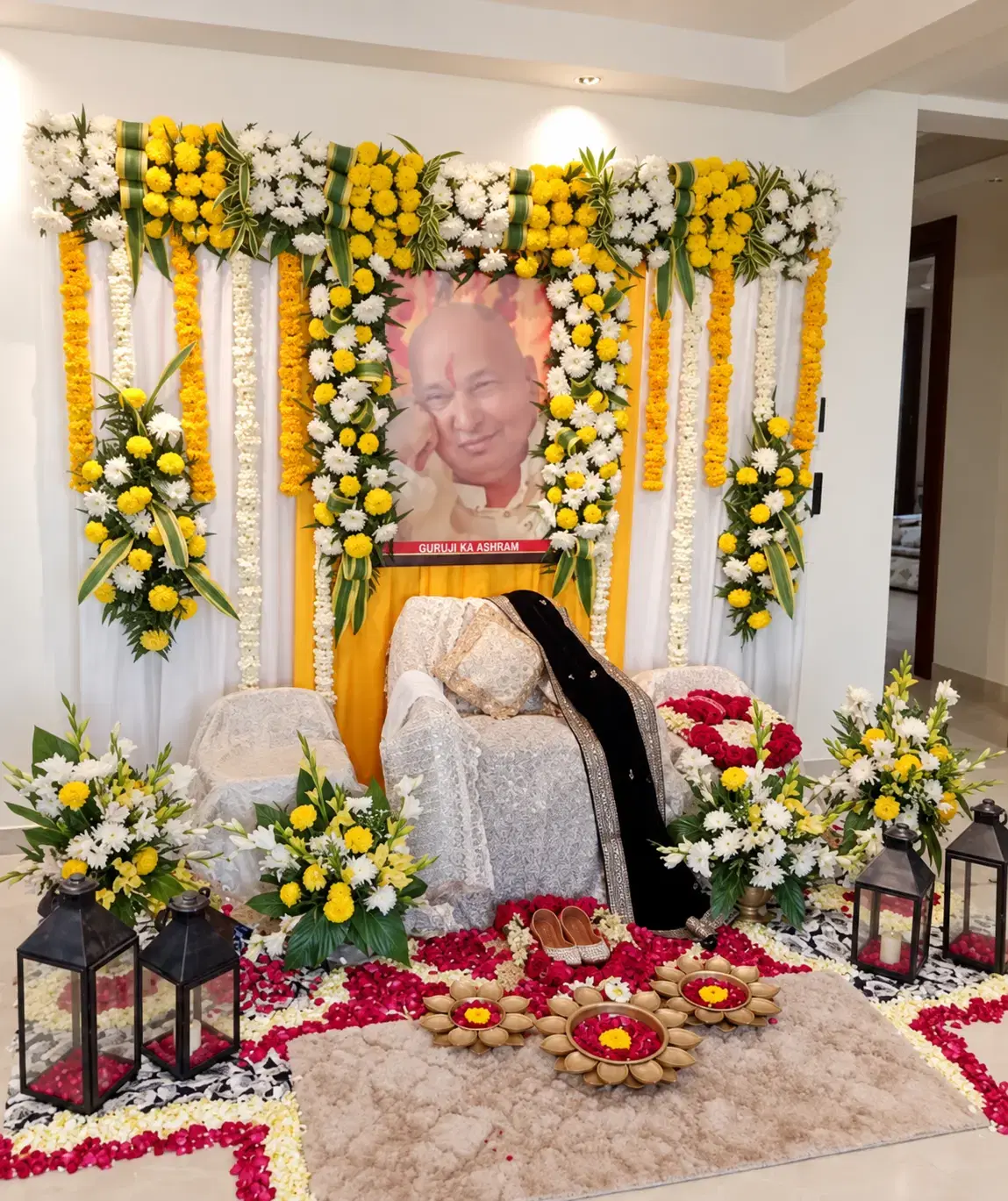 Religious ceremony setup decorated with yellow and white flowers and hanging garlands